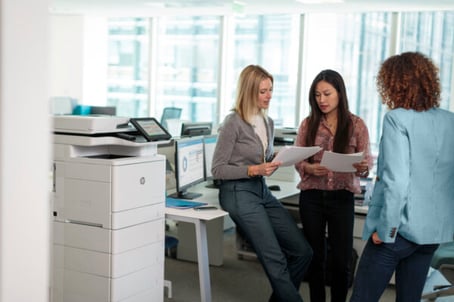 women back to the office and standing near an hp printer