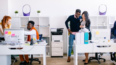 Coworkers in an office using managed print services for enterprises. 