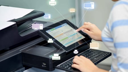 A person using a printer connected to a network of devices within an organization's hybrid workplace technology fleet.  
